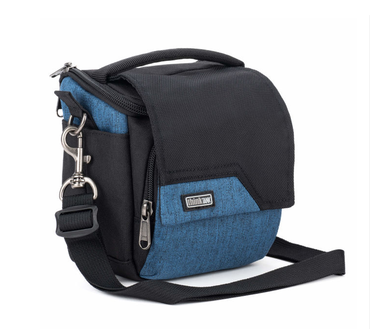 A small crossbody camera bag with a black and blue textured fabric design, featuring a top handle, front zippered pocket, side pocket, and an adjustable black shoulder strap with silver hardware.