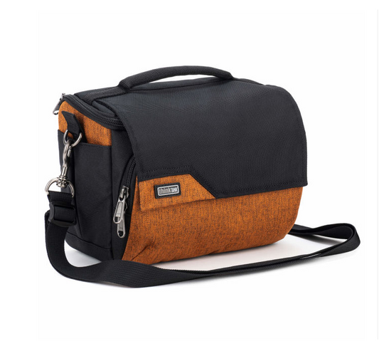 A black and orange camera bag with a top handle, front zippered pocket, and adjustable shoulder strap, shown on a white background.