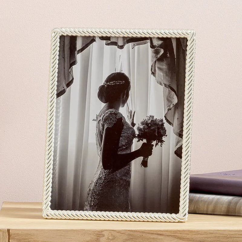 Framed black and white photo of a bride holding a bouquet on a wooden surface.